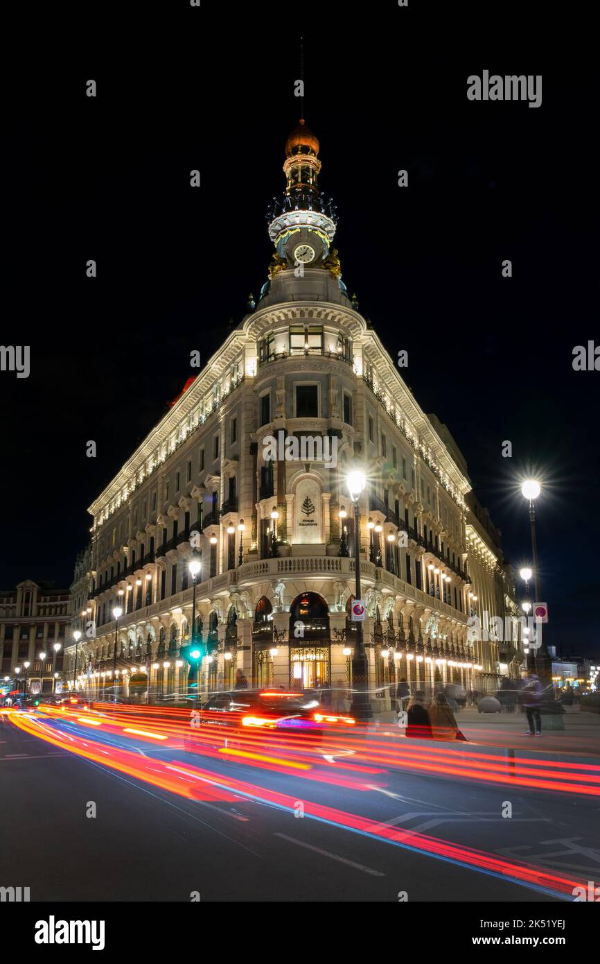 Four Seasons hotel in a beautiful building illuminated at night in Madrid with car light trails Stock Photo