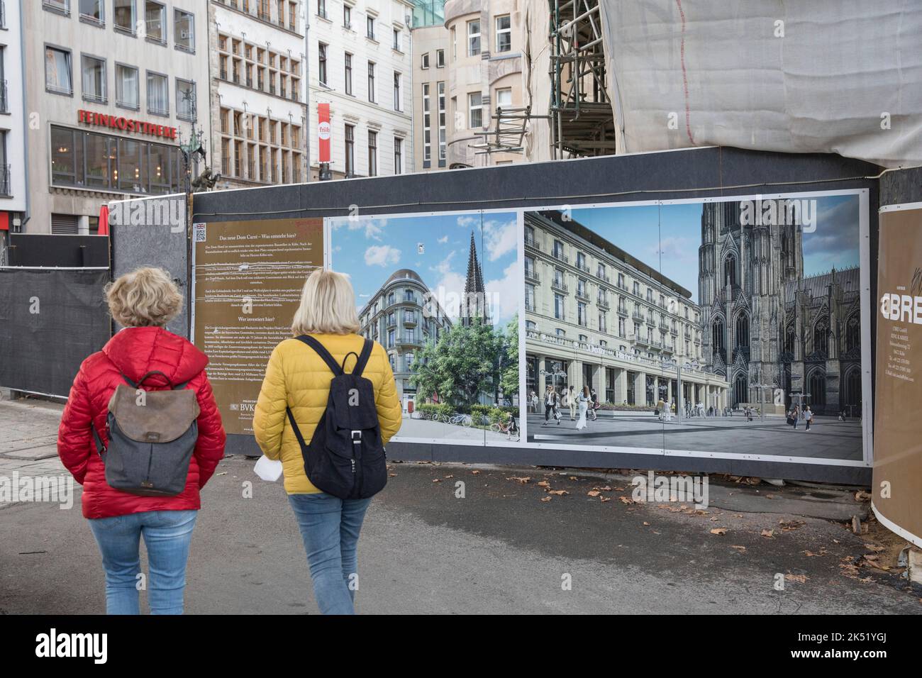 two women pass a construction fence with photos of the future state at the construction site of the Dom Hotel, Cologne, Germany. zwei Frauen passieren Stock Photo