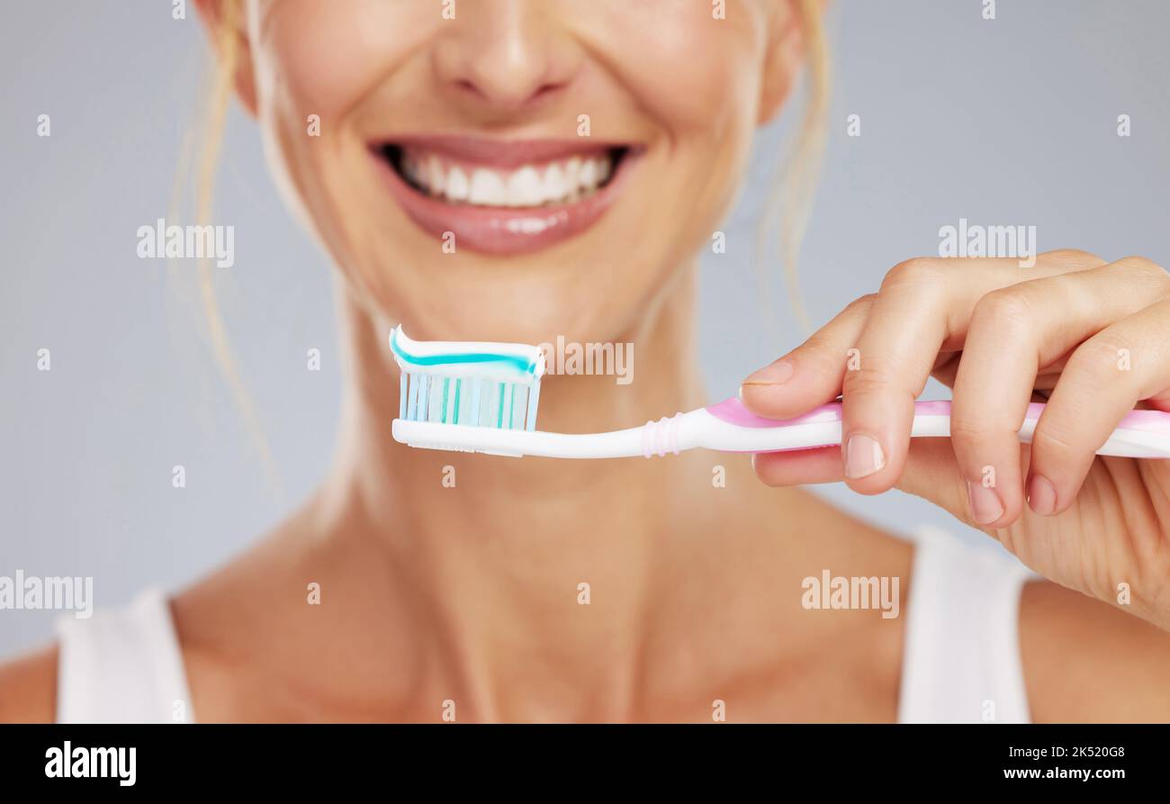 Toothpaste, hand and toothbrush in morning smile with clean teeth, wellness and dental healthcare in mockup studio background. Zoom of mouth cleaning Stock Photo