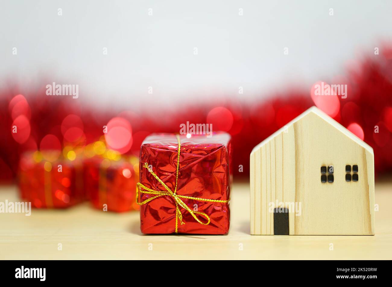 Red gift box and wooden house model in the concept of New Year and Christmas. Stock Photo