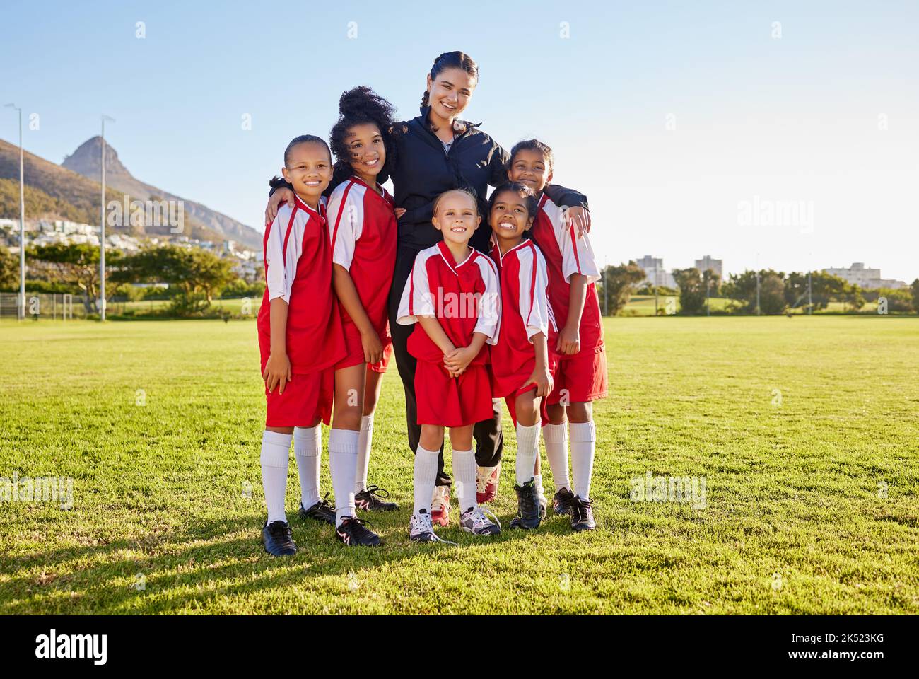 Team, soccer and coach smile on field together in portrait after training, game or workout in sun. Football, girl and woman with diversity in happy Stock Photo