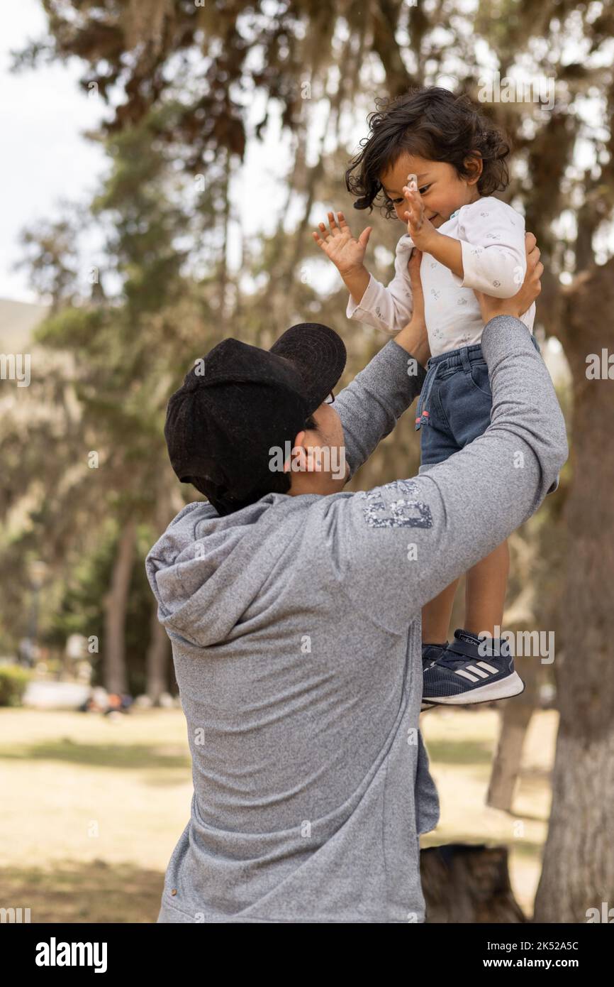 father playing with his son in a park on a sunny day, family love and care in childhood, lifestyle having fun Stock Photo