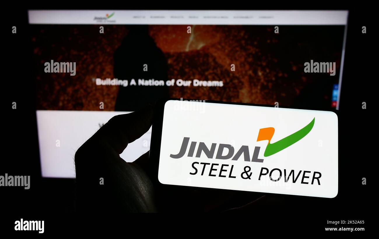 Person holding mobile phone with logo of company Jindal Steel and Power Limited (JSPL) on screen