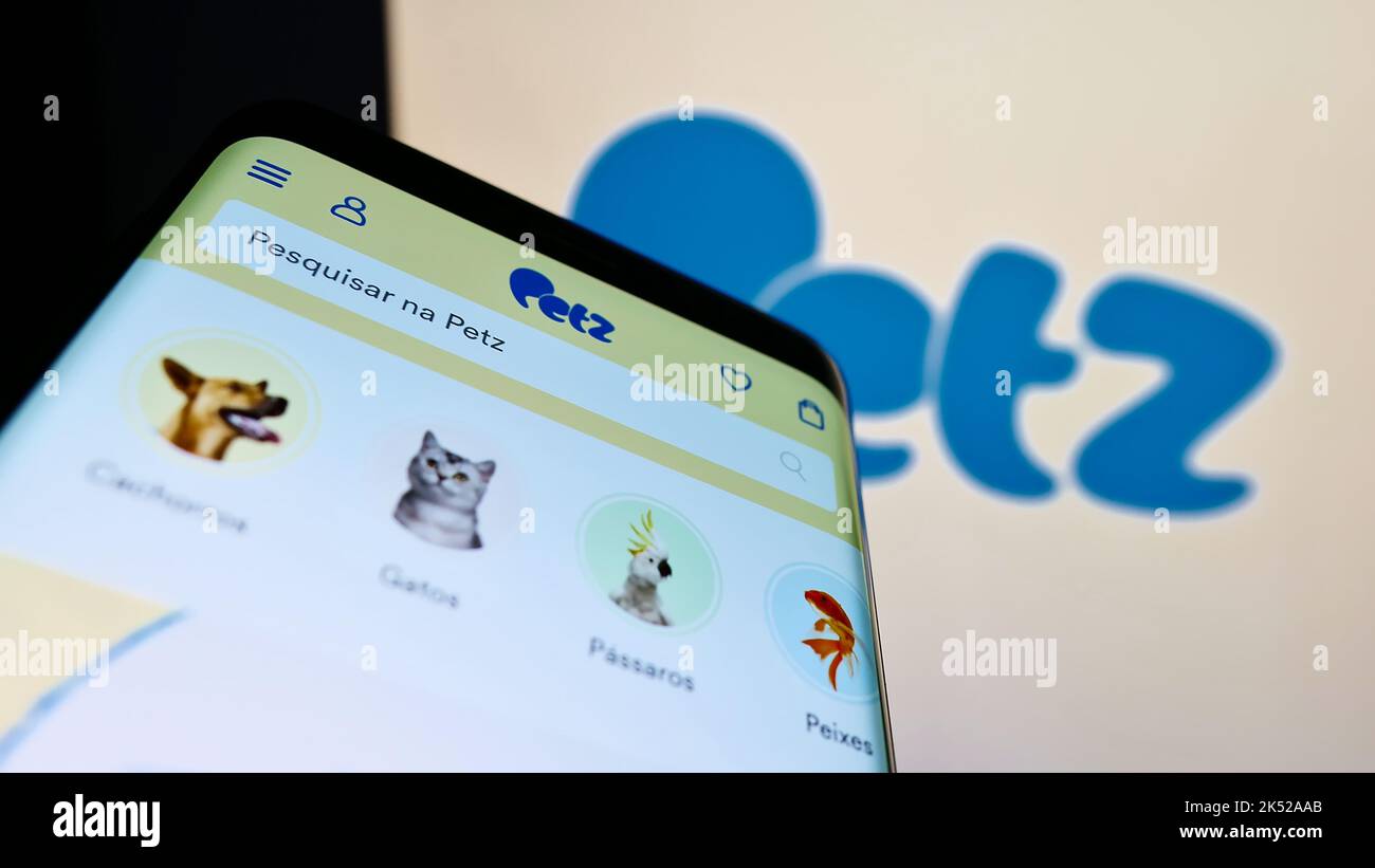 Smartphone with website of Pet Center Comercio Participacoes SA (Petz) on screen in front of business logo. Focus on top-left of phone display. Stock Photo