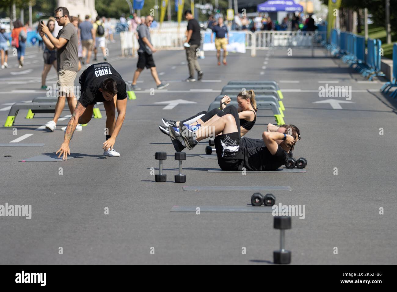 People doing sports in the street with jumps, races, weights and on