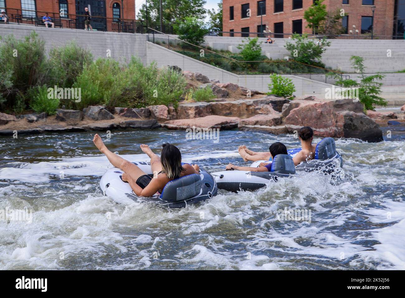 Friends have fun floating down the South Platte River in Denver on inflatable boats in Colorado USA Stock Photo