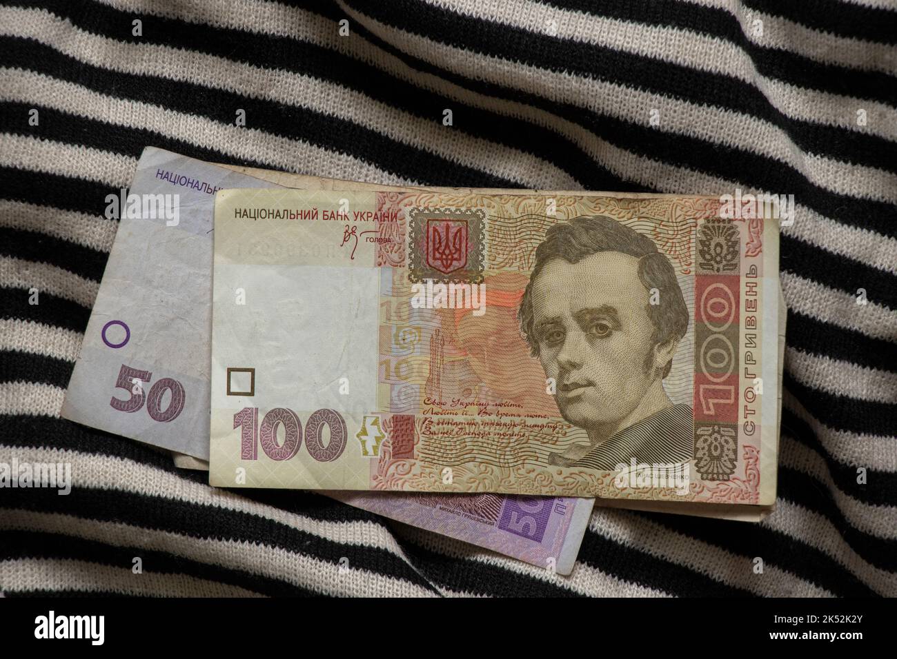 Ukrainian money one hundred and fifty hryvnia lie on a black and white striped background, Ukrainian money, finance Stock Photo