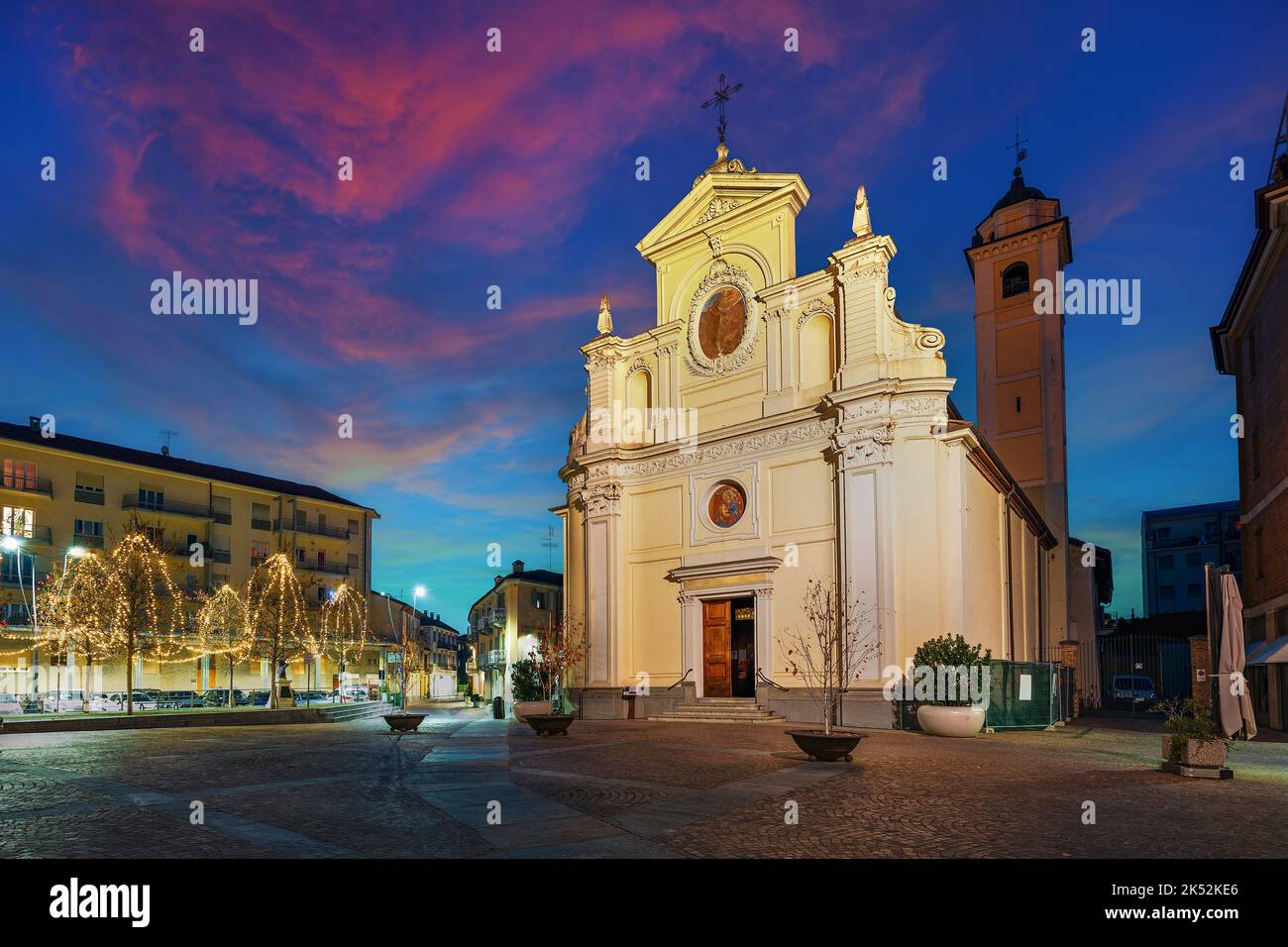 Catholic church on small town square illuminated with Christmas lights in the evening in Alba, Piedmont, Northern Italy. Stock Photo