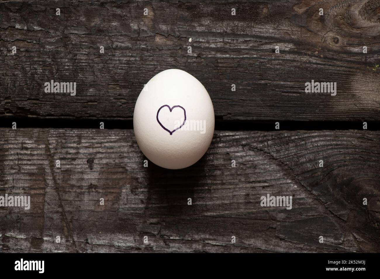 heart is drawn on a chicken egg that lies on an old wooden table, love and feelings Stock Photo