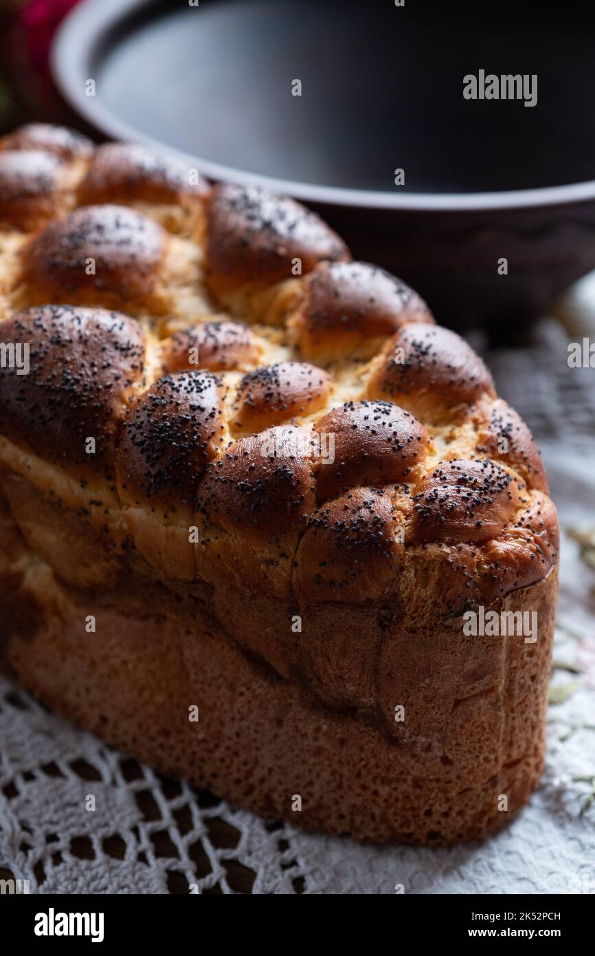 Braided bread sprinkled with poppy seeds on the textile napkin. Traditional East Slavic bread. Stock Photo