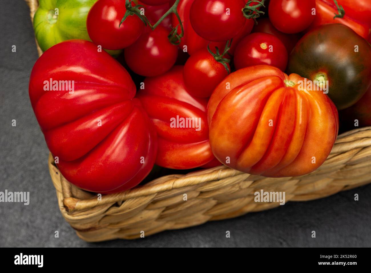 Red tomatoes in a wicker basket. Close up. Top vew. Black background ...