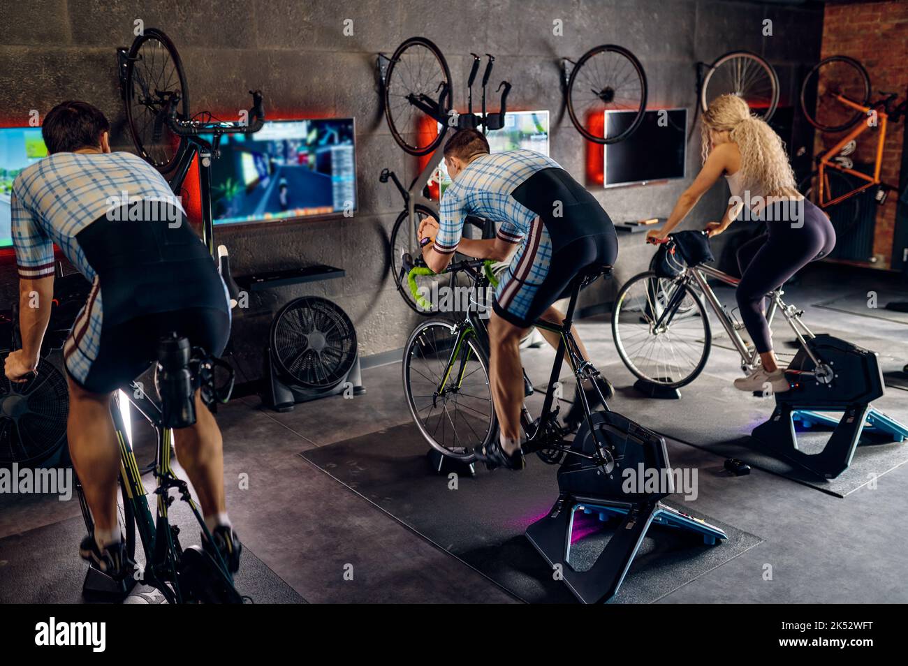 Sport people exercising on smart stationary bike at gym Stock Photo