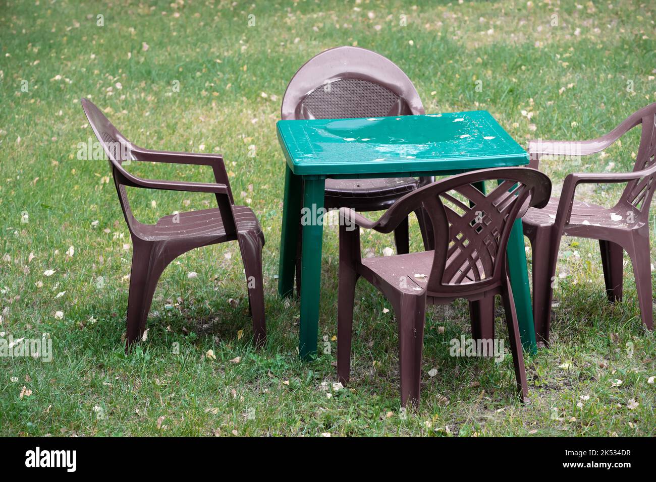 Messy and rainy plastic cafe chairs and table at autumn under the rain nasty day Stock Photo