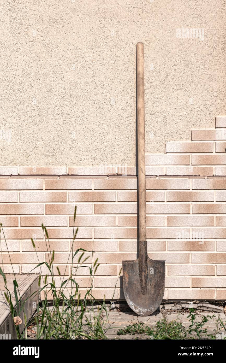 Old dirty filthy shovel against the tile wall summer day Stock Photo