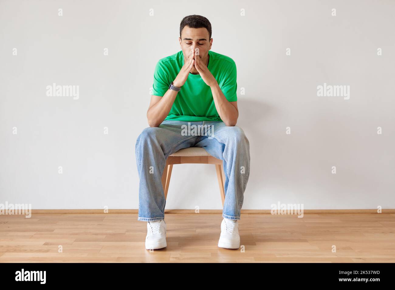 Portrait of pensive arab man sitting on chair at home and thinking about something, suffering life problems Stock Photo