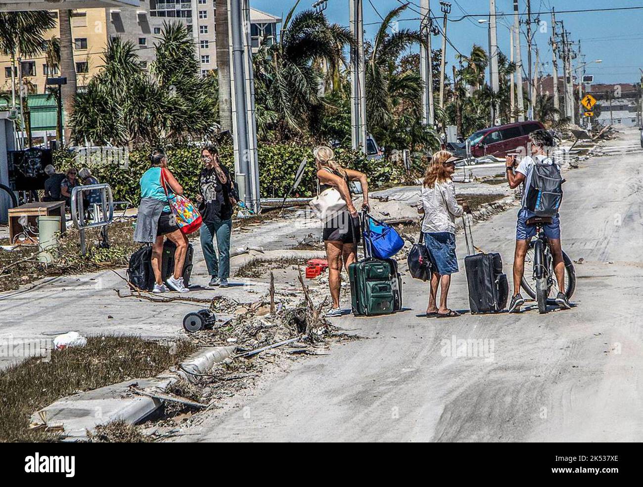Residents walk along Estero Boulevard with suitcases as they leave Fort