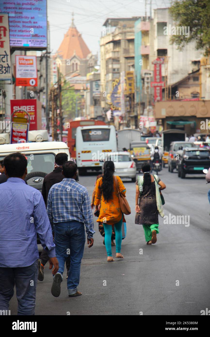 Indians walking on a busy street with many cars and signs Stock Photo