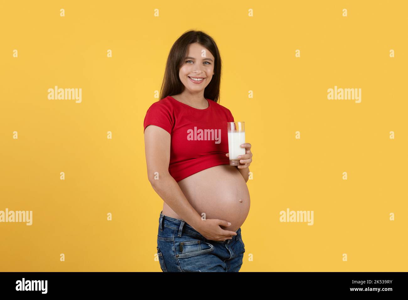 Portrait Of Beautiful Pregnant Woman Holding Glass With Milk And Touching Belly Stock Photo