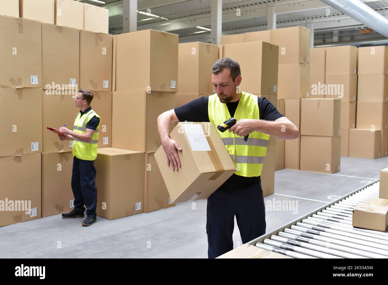 Worker in a warehouse in the logistics sector processing packages on the assembly line  - transport and processing of orders in trade Stock Photo