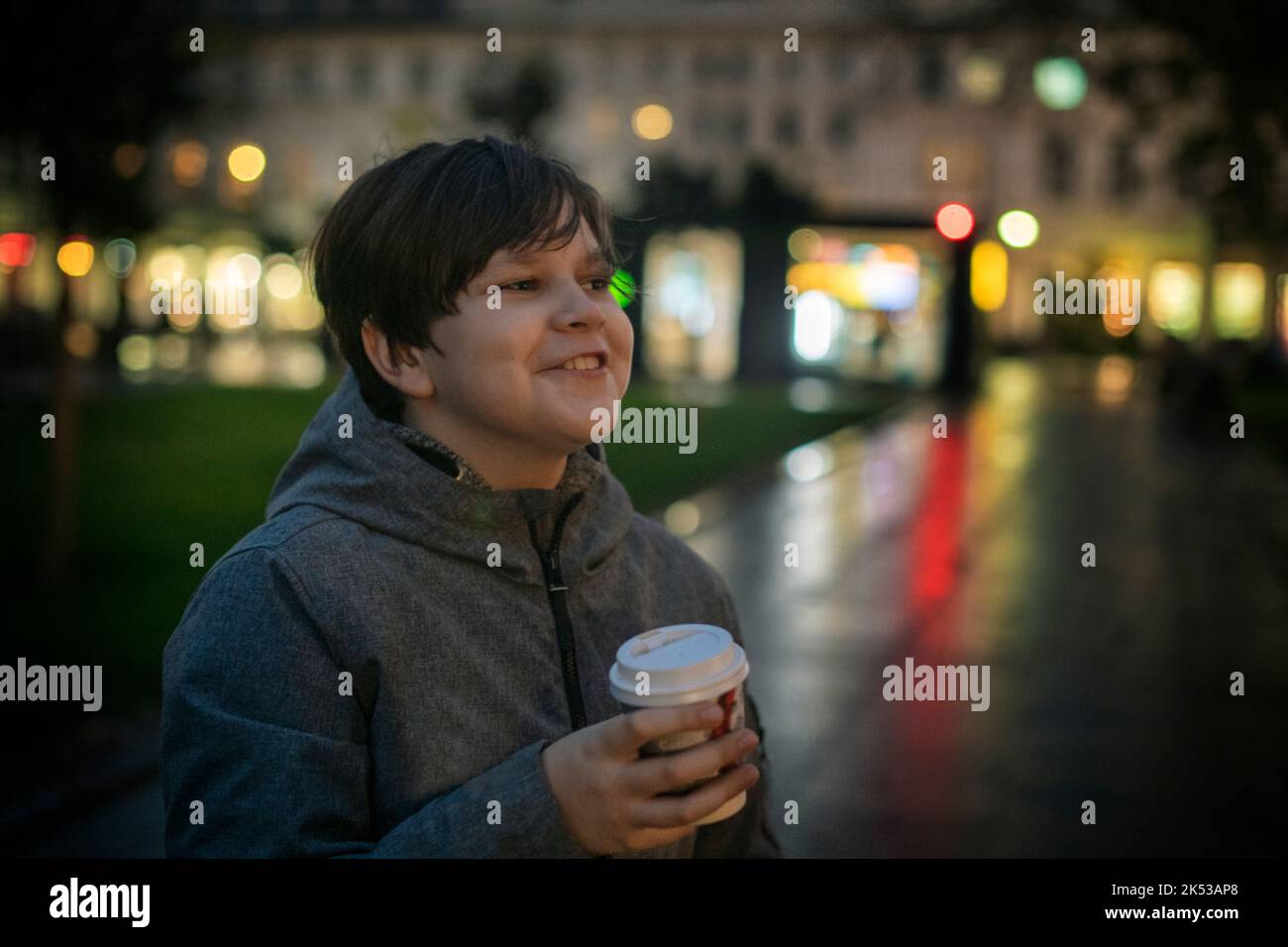 A teenager with positive emotions and a paper cup in his hand on the ...