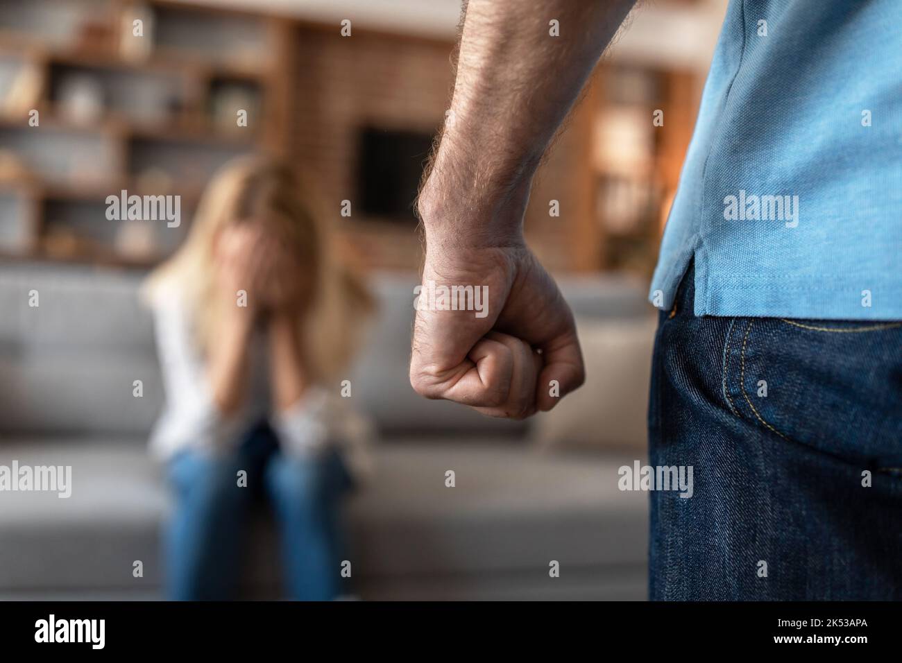 Frightened crying mature caucasian wife afraid of her husband, man threatening with fist Stock Photo