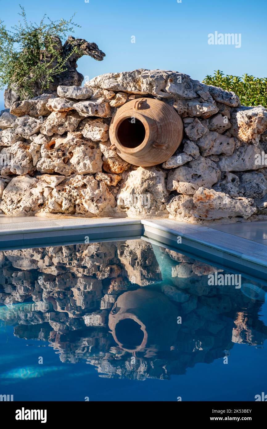 greek urn or olive storage jat set in a wall as decoration reflections in a swimming pool, olive oil jar used for decoaration on greek island of zante Stock Photo