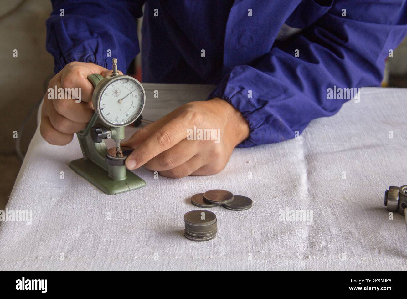 the hands of a mechanic in his workshop who, with a thickness gauge precision instrument, measures mechanical parts. Related to precision mechanics Stock Photo