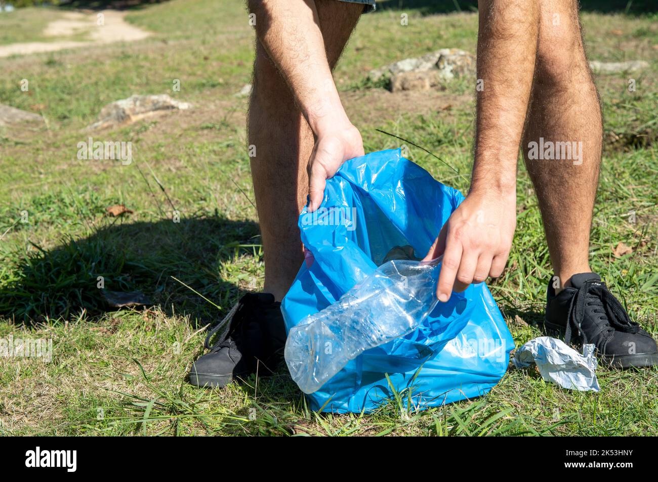 Young man cleaning up plastics from field. Collecting garbage in a plastic bag Stock Photo Alamy