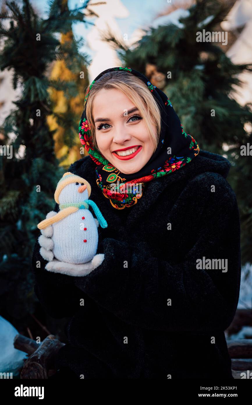 Beautiful young woman in a national Ukrainian headscarf holds a snowman  Stock Photo