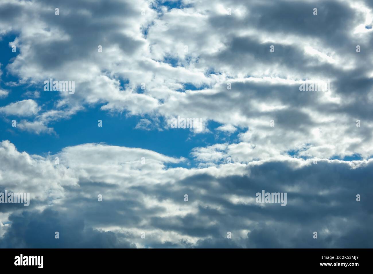 Blue sky with thunderclouds. The sun breaks through the clouds. Black clouds. Stock Photo