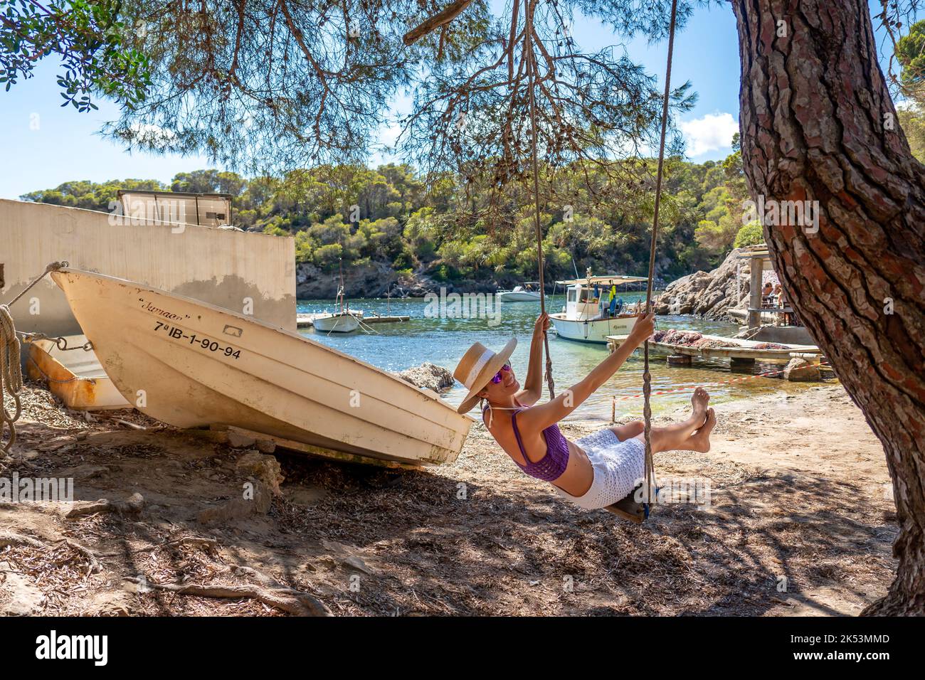 Woman on a swing on the shore of a Mediterranean cove Stock Photo