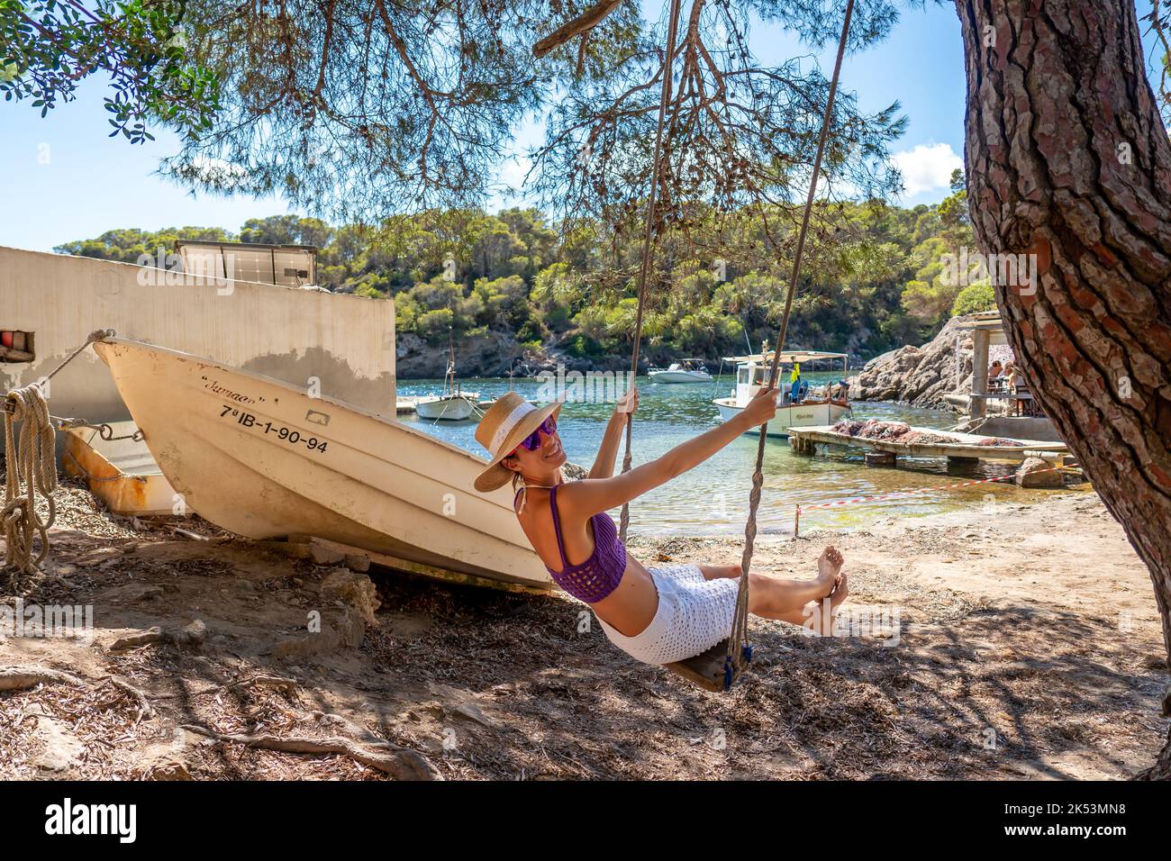 Woman on a swing on the shore of a Mediterranean cove Stock Photo