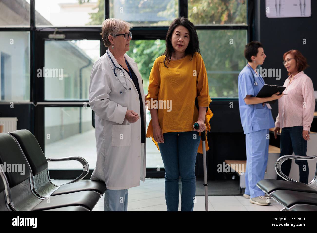 Elderly medic helping injured patient to walk with stick, suffering