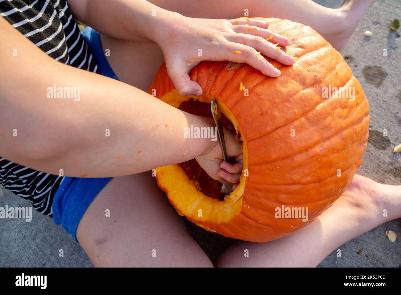 Close up of a girl's hands scooping out the inside of a pumpkin to make