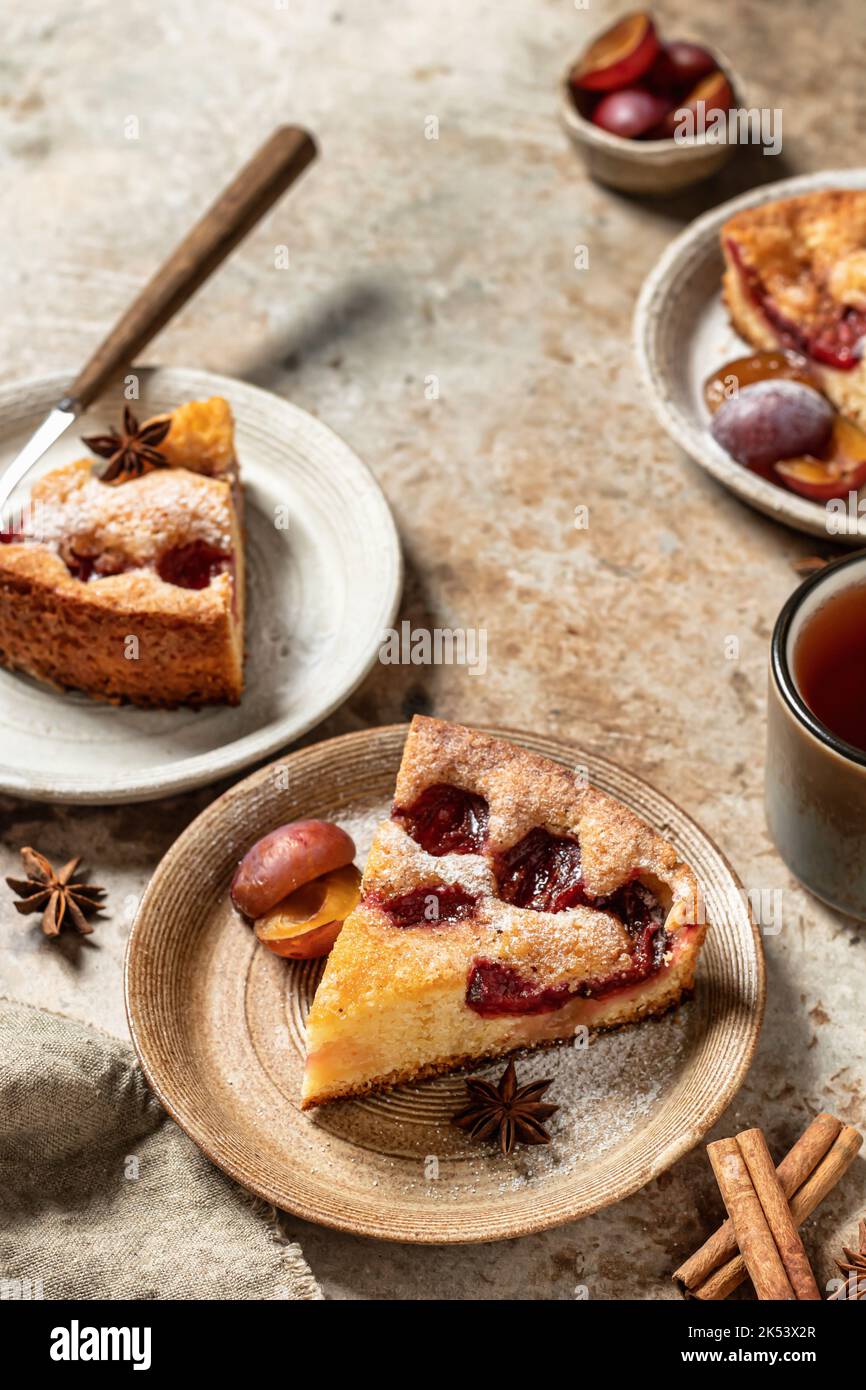 Plum pie pieces or The New York Times Famous Plum Torte with spices and tea on textured background, recipe in rustic style Stock Photo