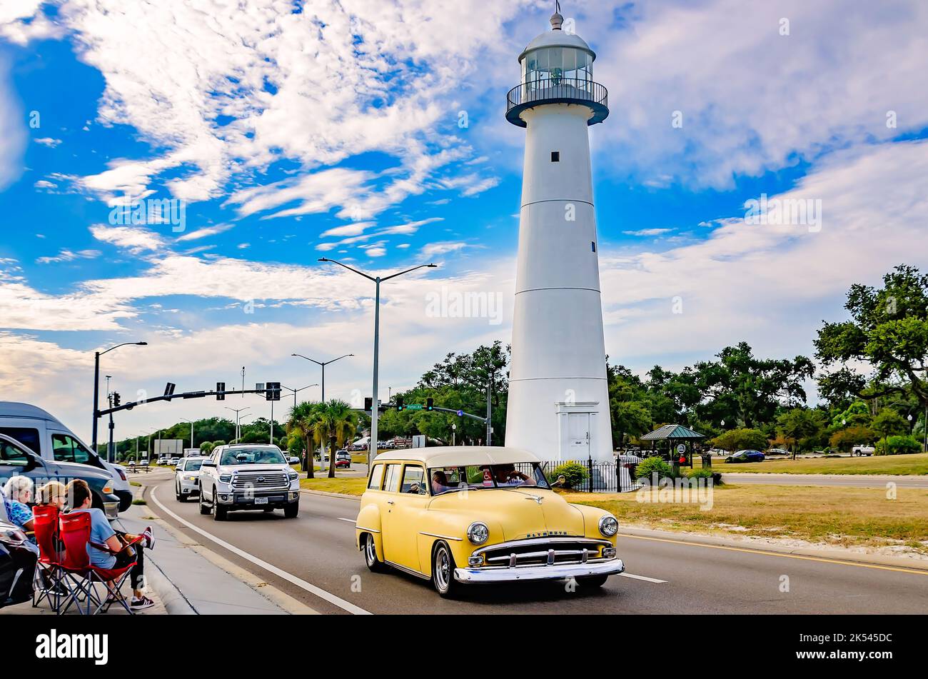 A vintage Plymouth automobile passes the Biloxi lighthouse during the