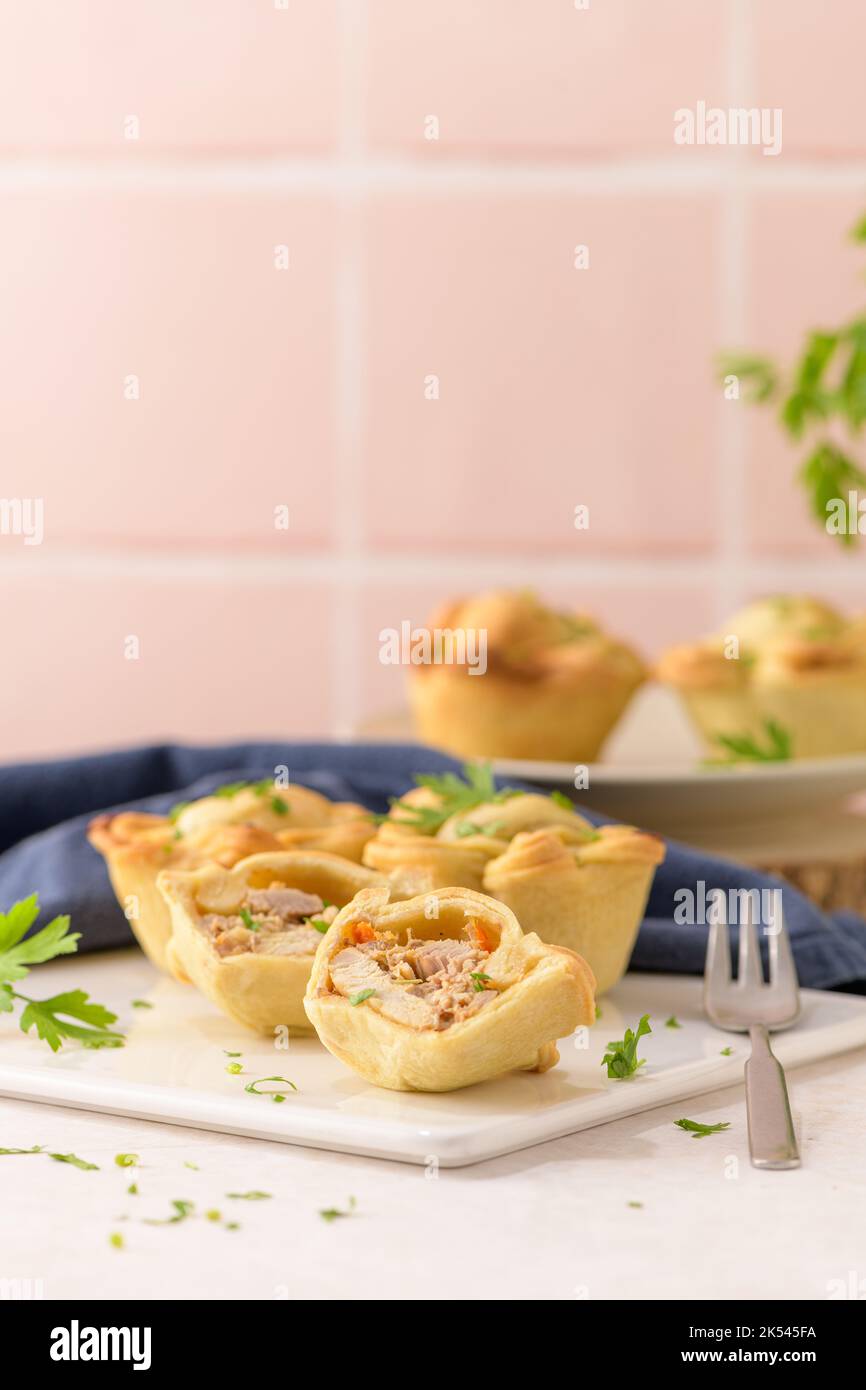 Chicken pies and parsley leaves on white ceramic dishes in a kitchen