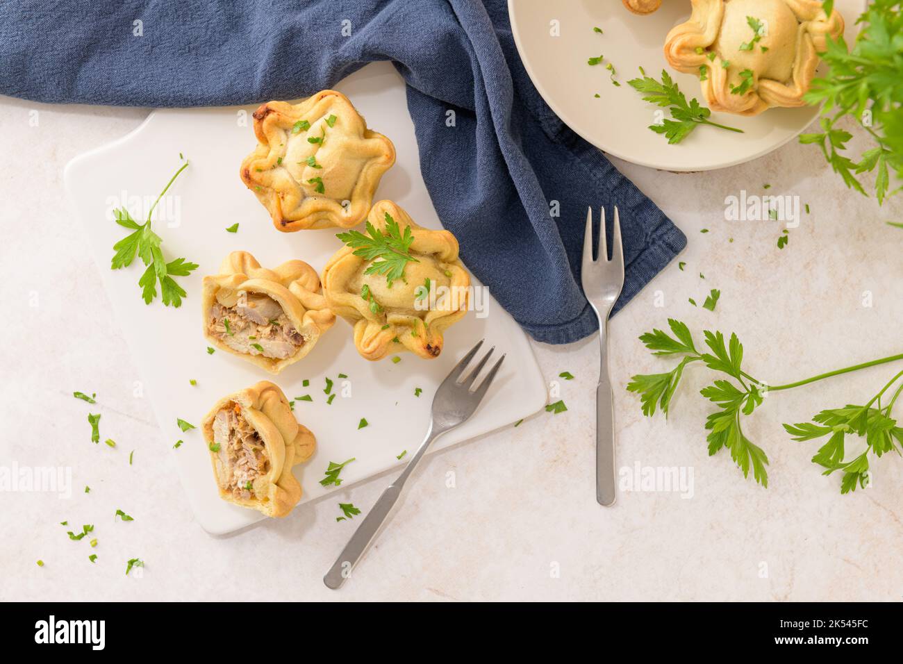 Chicken pies and parsley leaves on white ceramic dishes in a kitchen