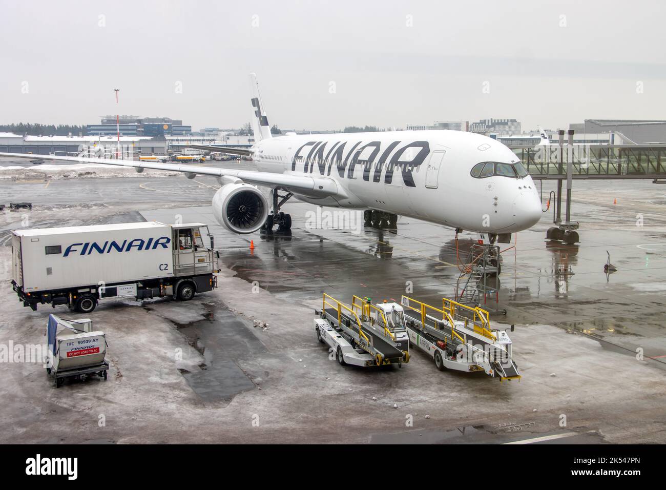 HELSINKI, FINLAND, FEB 15 2022, A delivery truck arrives at the plane at the snowy airport Stock Photo
