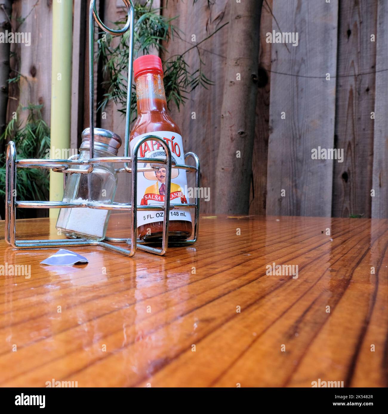 Tapatio hot sauce bottle and salt shaker in a metal condiment caddy on