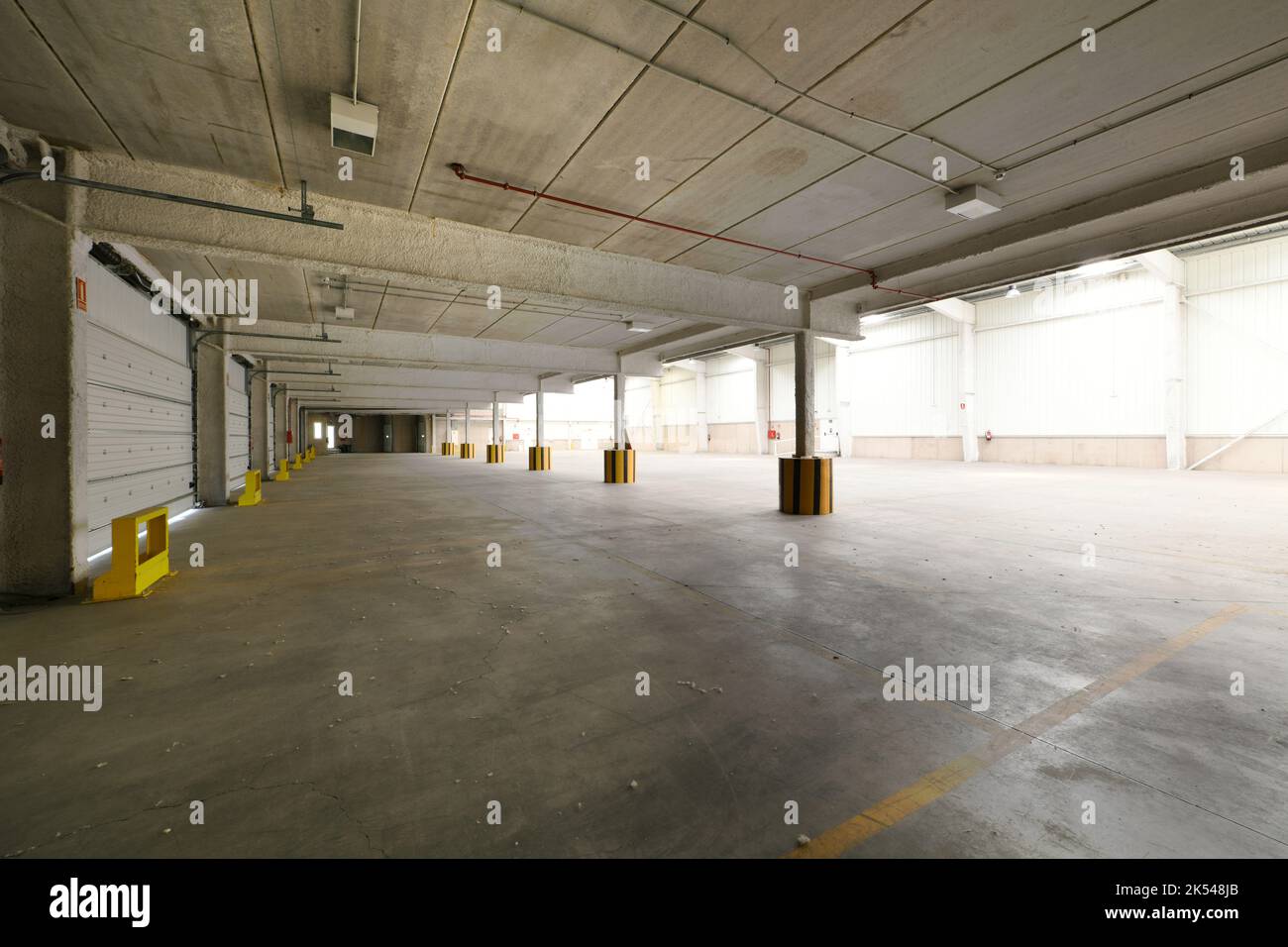 Empty industrial building with concrete floors, precast concrete rib beams, metal sliding doors Stock Photo