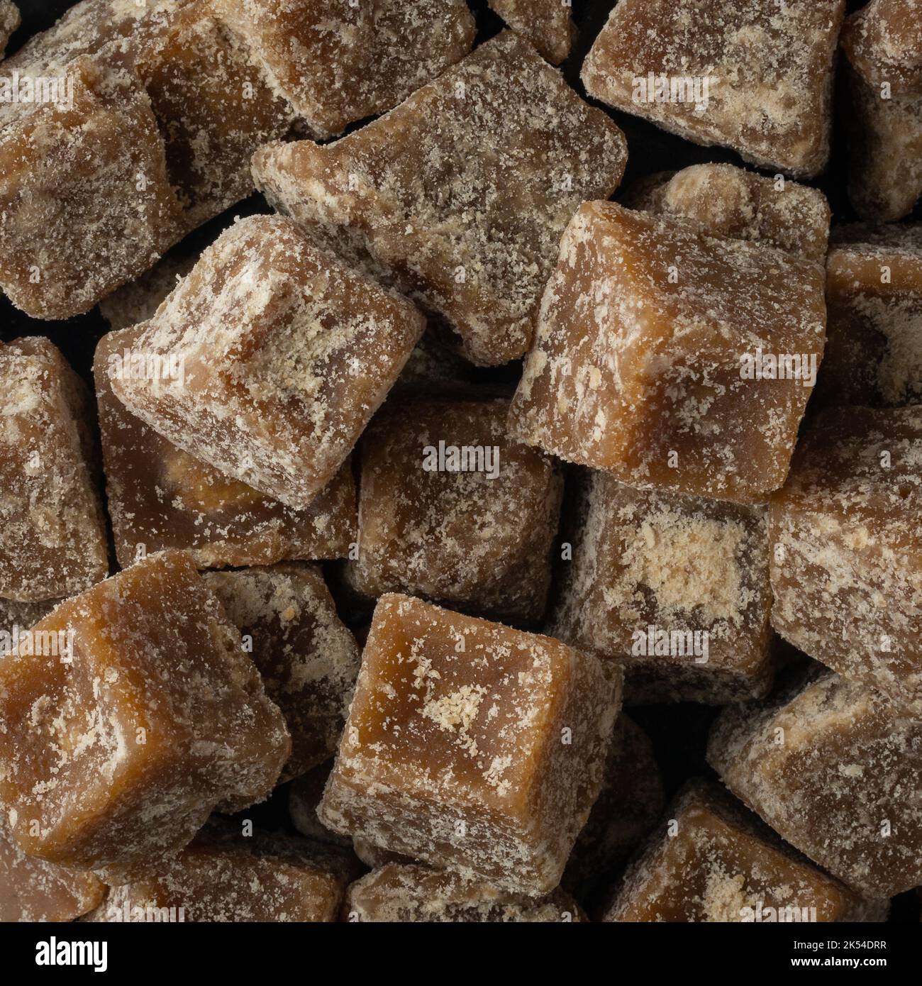 pile of jaggery pieces, golden brown colored cube shaped unrefined