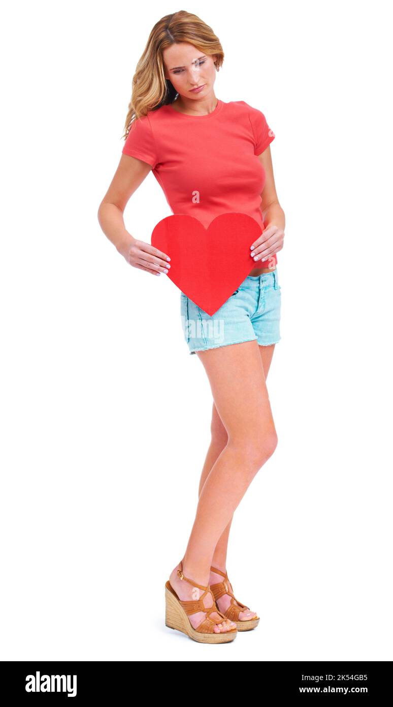 When will I meet the one. A sad young woman holding a heart-shaped placard while isolated on a white background. Stock Photo