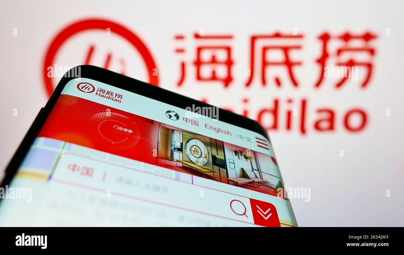 Mobile phone with website of company Haidilao International Holding Ltd. on screen in front of business logo. Focus on top-left of phone display. Stock Photo