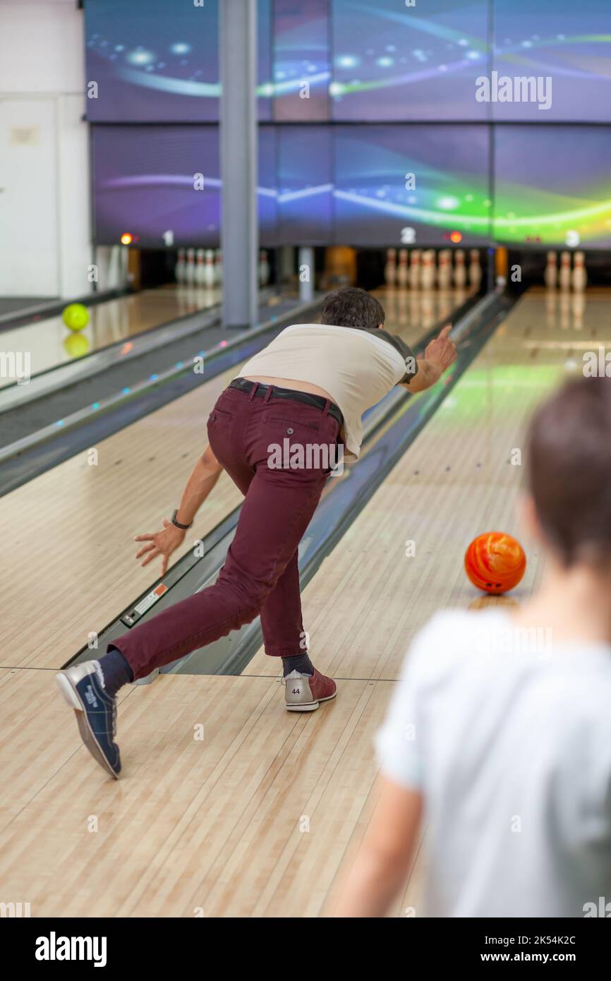 A man throws a ball into a bowling alley. Paths with balls and pins for