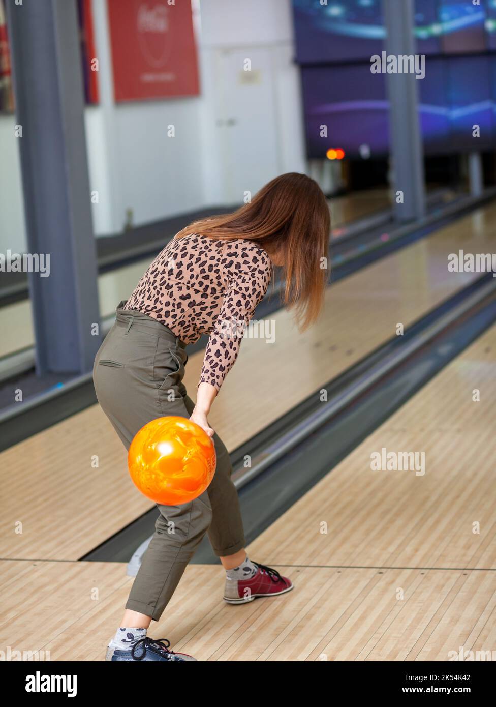 A woman throws a ball into a bowling alley. Paths with balls and pins