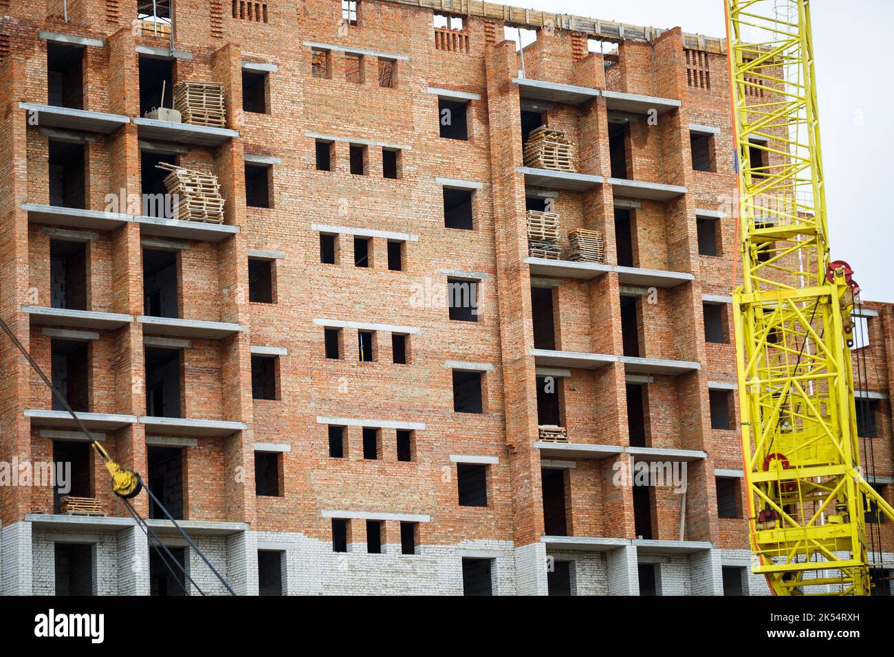 Big yellow construction crane on a background of a brick house. The