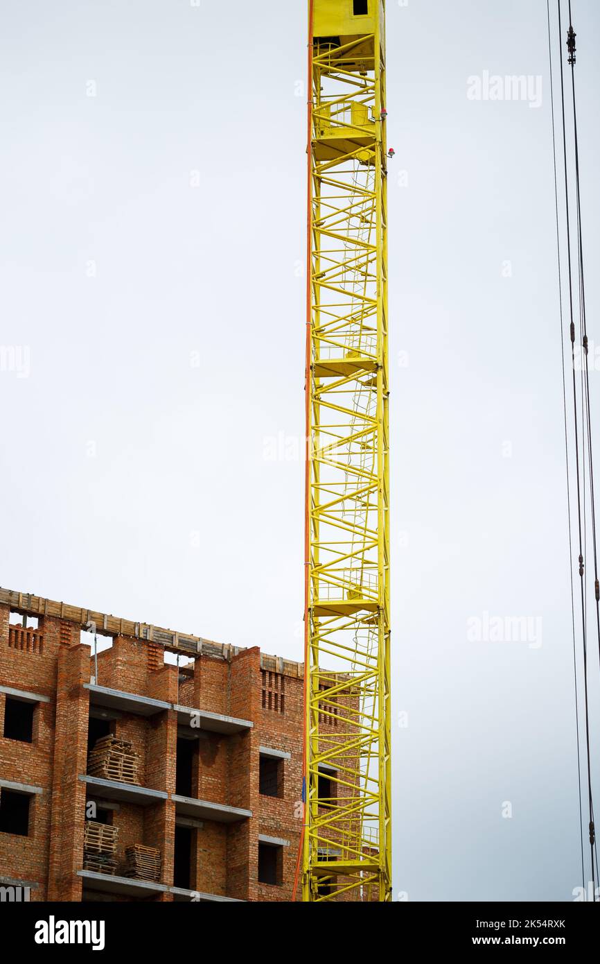 Big yellow construction crane on a background of a brick house. The