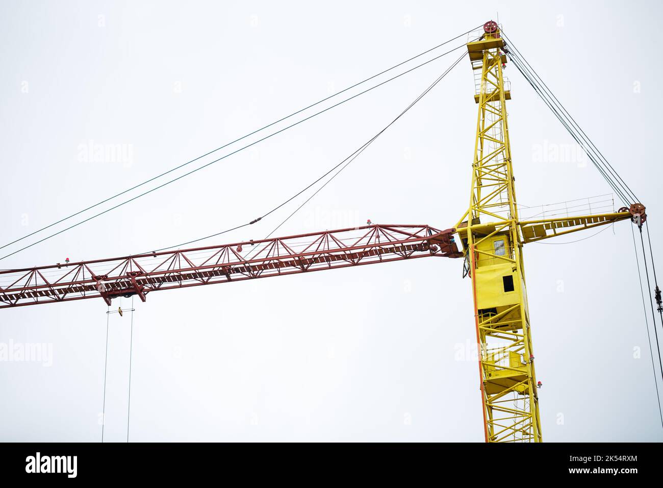 Big yellow construction crane on a background of a brick house. The