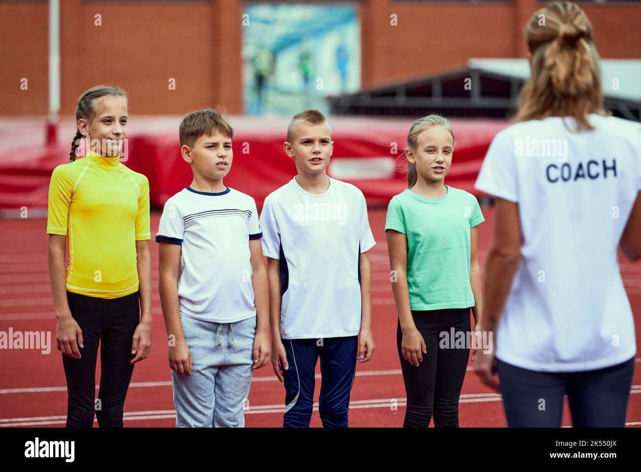 Female coach training athletes. Group of children before running on treadmill at the stadium. Concept of sport, achievements, studying, goals, skills Stock Photo